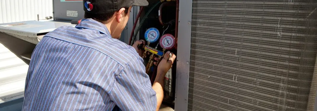 HVAC technician servicing a condenser unit in Parkway